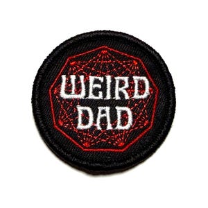 May include: Round black patch with the words "WEIRD DAD" in white, embroidered over a red geometric design. The patch has a red border and is suitable for jackets, bags, or other fabric items.
