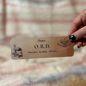 May include: A brown bookmark with the text "I have O.R.D. Obsessive Reading Disorder" and illustrations of a stack of books and a book with flowers.