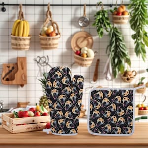 Può includere: Set di guanto da forno e presina neri con un motivo ripetuto di una faccia di cane. Il guanto e la presina hanno un design trapuntato con bordi bianchi. Il set è esposto su una superficie di legno in un ambiente cucina.