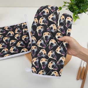Könnte beinhalten: Schwarzes Ofenhandschuh- und Topflappen-Set mit einem sich wiederholenden Muster von Hundegesichtern. Der Handschuh ist gesteppt und hat ein Drei-Finger-Design. Der Topflappen ist quadratisch mit weißem Rand. Küchenzubehör.