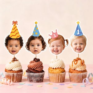 Peut inclure: Quatre décorations pour cupcakes représentant des visages de bébés avec des chapeaux de fête et une couronne. Les chapeaux incluent un motif ondulé orange, des étoiles bleues, une couronne rose avec le chiffre 1 et un chapeau bleu avec le chiffre 1.