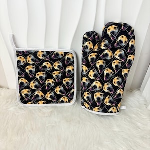 Könnte beinhalten: Ein Set aus zwei schwarzen und weißen Topflappen mit einem sich wiederholenden Muster eines Hundefaces. Die Topflappen sind gesteppt und haben einen weißen Rand.