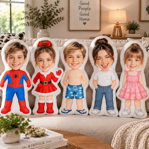 May include: Five custom-shaped plush pillows featuring cartoon-style illustrations of children. The figures include a child in a red and blue superhero suit, a child in a red Santa dress, a child in blue swim trunks, a child in a white t-shirt and blue jeans, and a child in a pink dress.