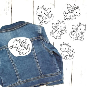 May include: A denim jacket with a patch featuring a black and white cartoon dragon. Several other dragon patches are scattered around the jacket. The dragons have wings and are in various poses.