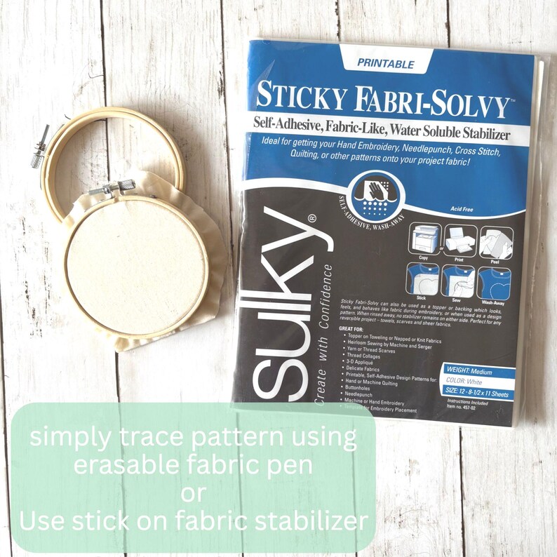 May include: An embroidery hoop with fabric and a package of Sulky Sticky Fabri-Solvy, a self-adhesive, fabric-like, water-soluble stabilizer. The package is blue and black with white text. Text on the image reads: "simply trace pattern using erasable fabric pen or Use stick on fabric stabilizer."
