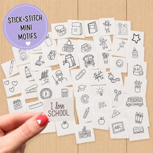 May include: A collection of white square stick-and-stitch embroidery motifs featuring black line art illustrations of school-themed items like a bus, books, pencils, and a chalkboard. One motif held in the foreground displays the text I love SCHOOL.