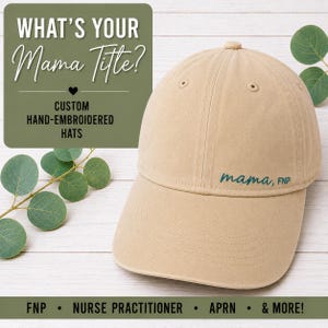 May include: A beige baseball cap featuring the dark teal embroidered text "mama, FNP" on the front panel. The cap has a structured crown, a curved brim, and stitched eyelets. The text "WHAT'S YOUR Mama Title?" and "CUSTOM HAND-EMBROIDERED HATS" appear nearby.