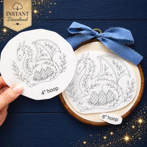 May include: Two white fabric pieces featuring a black line art dragon and egg design. One piece is labelled 4" hoop and the other is mounted in a wooden embroidery hoop with a blue ribbon, labelled 6" hoop. The design includes floral accents.