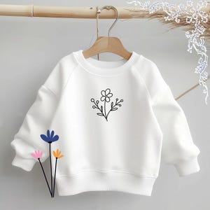 May include: A white long-sleeve sweatshirt featuring a central black line-art floral graphic. The garment has a crew neckline, ribbed cuffs, and a ribbed hem. Below the sweatshirt, three stylized flower illustrations appear in blue, pink, and orange.