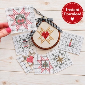 May include: A cross-stitch pattern set featuring six square grid charts and one circular wooden embroidery hoop ornament. The hoop displays a gold star and red heart design, accented with a black and white gingham ribbon bow.