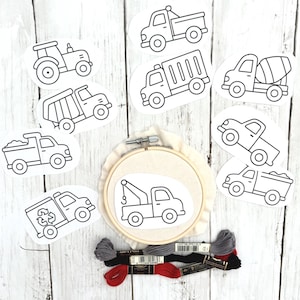 May include: A collection of truck-themed embroidery supplies. Includes a wooden embroidery hoop with a tow truck design, several truck outline stickers, and spools of embroidery floss in red, black, and gray.