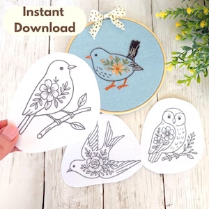 Puede incluir: Un bastidor de bordado con un diseño de pájaro azul y varios patrones de bordado de pájaros. Los patrones incluyen un pájaro en una rama, un pájaro volando y un búho. El texto "Instant Download" está en la parte superior.