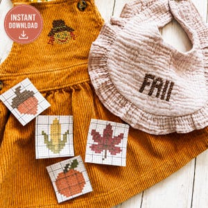 Puede incluir: Un vestido de peto de pana color amarillo mostaza con un espantapájaros en punto de cruz, junto a un babero de muselina rosa claro con volantes y el texto "FALL" bordado. Incluye cuatro patrones de punto de cruz de bellota, maíz, hoja y calabaza.