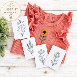 May include: A coral-colored ribbed baby bodysuit with ruffled sleeves and a sunflower embroidery, accompanied by four white rectangular cards featuring black line art illustrations of various wildflowers, including a bellflower and daisy.