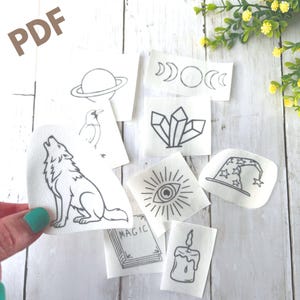 Peut inclure: Un ensemble de patchs en tissu blanc avec des illustrations au trait noir. Les motifs comprennent un loup hurlant, une planète, des cristaux, un œil, des croissants de lune, un corbeau, un chapeau de sorcier, une bougie et un livre avec le mot "MAGIC". Le mot "PDF" est en haut à gauche.