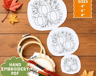 May include: A hand embroidery kit featuring three white fabric circles with black line art of pumpkins and flowers. Includes three wooden hoops in 4, 6, and 8 inch sizes, and three skeins of embroidery floss in orange, rust, and green colors.