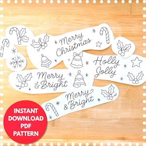 Peut inclure: Découpes de papier blanc avec des dessins au trait noirs sur le thème de Noël, notamment des cannes en sucre, des cloches, du houx et des flocons de neige. Le texte comprend "Merry Christmas", "Holly Jolly" et "Merry & Bright". Un cercle rouge indique "Téléchargement instantané PDF Pattern."