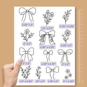 May include: A white sheet featuring black line art illustrations of various bows and floral sprigs. Each design includes a purple label with dimensions in inches, such as 2.25" x 2", 1.5" x 2.5", and 1.25" x 2.25". A vertical metric ruler is visible on the right side.