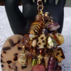 Dije para bolso estilo bohemio. Cadena y llavero dorados. Cuentas con estampado de leopardo y colgantes marrones, beige y dorados.