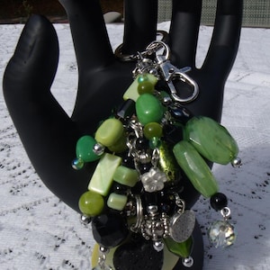 Dije para bolso brillante y alegre. Cadena y llavero de plata. Dije colgante en tonos verde, negro y plata con colgante en la base.