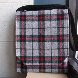 May include: A grey and black plaid messenger bag with red accents. The bag has a flap closure and a long adjustable strap.