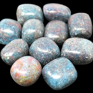 May include: A collection of tumbled stones with a mix of blue, red, and gray hues. The stones have a smooth, polished appearance and are arranged against a black background. These stones are likely used for decorative or metaphysical purposes.