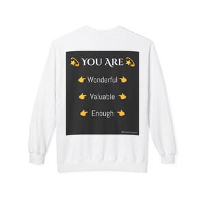 May include: White long-sleeve sweatshirt with a black square graphic on the back that says "YOU ARE" with three lines of text below: "Wonderful", "Valuable", and "Enough". Each line of text has a yellow pointing hand emoji on either side.