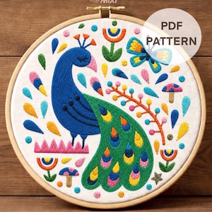 May include: A colorful embroidery hoop featuring a peacock design. The peacock is primarily blue and green, with a detailed tail. The design includes a butterfly, flowers, and the text "PDF PATTERN". The embroidery is set in a wooden hoop.