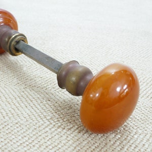 May include: A vintage door knob with a brass base and two amber glass knobs. The knobs are round and have a smooth, glossy finish.