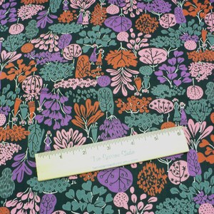 May include: A dark green fabric with a repeating pattern of pink, purple, orange, and white stylized trees and figures. A ruler with the text "Two Sparrow Studio" is placed on top of the fabric.