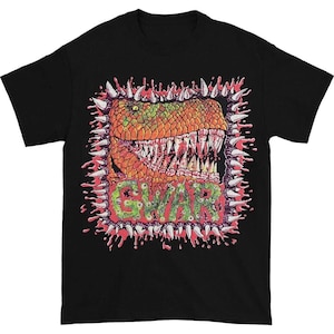 Puede incluir: Camiseta negra con un gráfico colorido de una cabeza de dinosaurio con dientes afilados, rodeada por un marco de púas y salpicaduras de sangre. La palabra "GWAR" está impresa en verde con ojos.