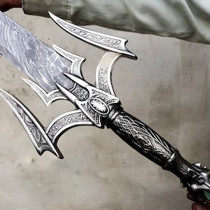 May include: A silver sword with a decorative, intricate design. The blade is made of Damascus steel and the handle is adorned with a dragon head.