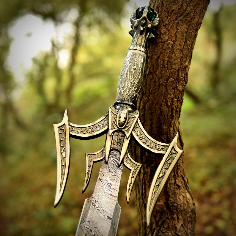 May include: An ornate sword with a detailed hilt and a patterned blade. The sword has a gold and silver color scheme, with intricate designs on the handle and guard. The blade has a unique, textured appearance. The sword is leaning against a tree.
