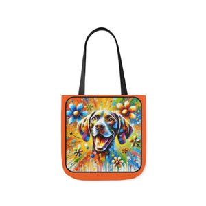 May include: A colourful tote bag featuring a painting of a dog's face surrounded by flowers. The dog is brown and black with a white chest and a happy expression. The background is a vibrant mix of colours, including yellow, orange, red, blue, and green.