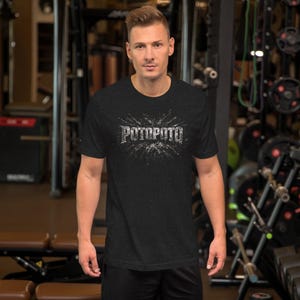 Op de afbeelding: Een donkergrijs gemêleerd T-shirt met korte mouwen en het woord POTOPOTO in een verweerd wit lettertype op de borst, omringd door een wit grafisch spat-effect dat vanuit het midden van de tekst naar buiten straalt.