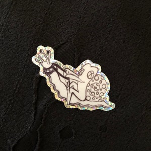 May include: A black and white line drawing of a snail with a crown on its head and a chain around its body. The snail is on a glittery background.