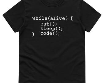 May include: Black t-shirt featuring the white text: "while(alive) { eat(); sleep(); } code();". The text is formatted like a code snippet. The shirt has a crew neck.