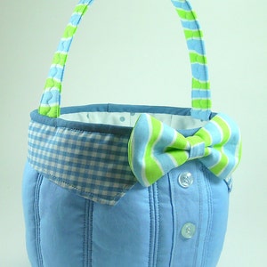May include: A blue and green fabric Easter basket shaped like a shirt with a bow tie and a gingham collar.
