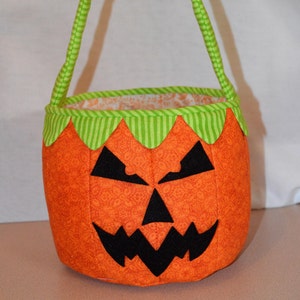 Peut inclure: Sac de bonbons d'Halloween orange et vert en forme de citrouille avec un visage noir effrayant.
