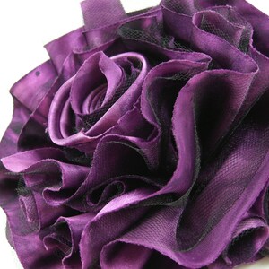K&ouml;nnte beinhalten: Eine gro&szlig;e, violette Stoffrose mit schwarzem Netz. Die Rose besteht aus mehreren Stofflagen und ist sehr voll.