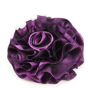 K&ouml;nnte beinhalten: Eine gro&szlig;e violette Stoffblume mit einer ger&uuml;schten Textur und schwarzen Netz-Akzenten.