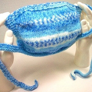 May include: A blue and white knitted face mask with long ties. The mask is made with a simple stitch pattern and has a white stripe in the middle.