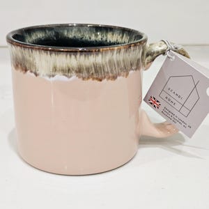 May include: A pink ceramic mug with a dark rim and a handle. The mug has a capacity of 17oz and a tag that reads "SCANDI HOME" and "Designed in London, UK".