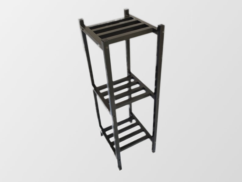 May include: A black metal plant stand with three rectangular shelves. The stand is made of square metal tubing and has a minimalist design. The shelves are supported by horizontal metal bars.