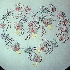 May include: A heart-shaped embroidery design featuring delicate pink and green flowers with yellow centers. The flowers are connected by a chain of small beads, creating a flowing and elegant pattern.