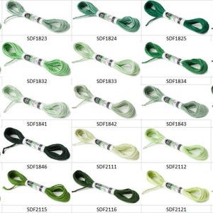 May include: A collection of twenty-five skeins of embroidery floss arranged in a grid, each featuring a unique shade of green or olive, labeled with codes ranging from SDF1822 to SDF2122, with each skein secured by a white paper band.