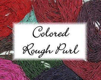 May include: A close-up of a variety of colored rough purl cord. The cord is arranged in a pile and is available in a variety of colors, including red, green, purple, and brown.