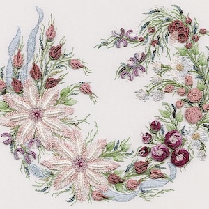 May include: A delicate floral embroidery design featuring pink and white flowers, green leaves, and blue ribbon accents. The design is arranged in a circular pattern, creating a wreath-like effect.