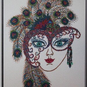 May include: Embroidered image of a woman's face wearing a masquerade mask with a peacock feather headdress. The mask is red, blue, and green with intricate details. The feathers are a mix of brown, green, and blue. The design area is 5.5 inches by 8 inches.