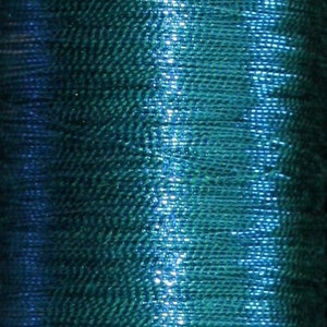 May include: A spool of teal and blue metallic thread. The thread is wound tightly around the spool and has a shiny, iridescent finish.